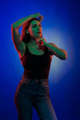 Young girl posing and moving in a black studio with colored light	