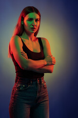 Young girl posing and moving in a black studio with colored light	