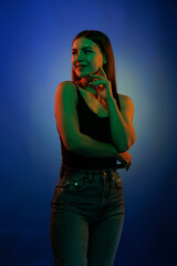 Young girl posing and moving in a black studio with colored light	