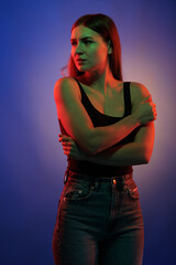 Young girl posing and moving in a black studio with colored light	