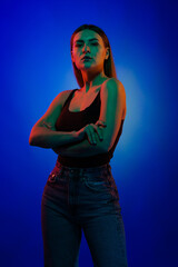 Young girl posing and moving in a black studio with colored light	