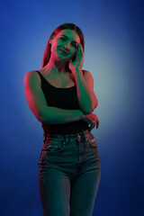 Young girl posing and moving in a black studio with colored light	