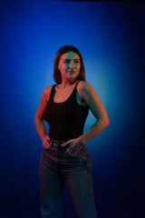 Young girl posing and moving in a black studio with colored light	