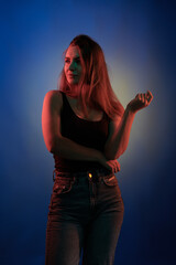 Young girl posing and moving in a black studio with colored light	