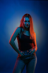 Young girl posing and moving in a black studio with colored light	