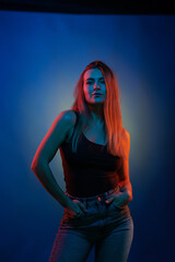 Young girl posing and moving in a black studio with colored light	