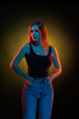 Young girl posing and moving in a black studio with colored light	