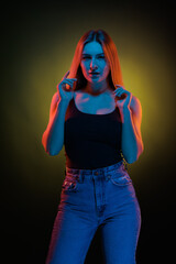 Young girl posing and moving in a black studio with colored light	