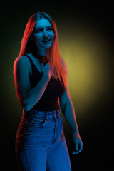 Young girl posing and moving in a black studio with colored light