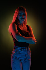 Young girl posing and moving in a black studio with colored light
