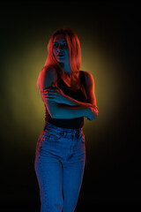 Young girl posing and moving in a black studio with colored light