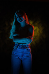Young girl posing and moving in a black studio with colored light