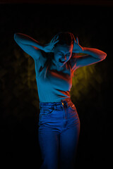 Young girl posing and moving in a black studio with colored light