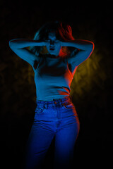 Young girl posing and moving in a black studio with colored light	
