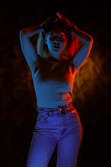Young girl posing and moving in a black studio with colored light	
