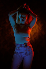 Young girl posing and moving in a black studio with colored light	