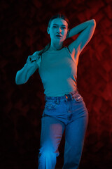 Young girl posing and moving in a black studio with colored light	