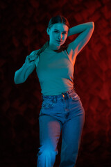Young girl posing and moving in a black studio with colored light	