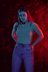 Young girl posing and moving in a black studio with colored light	