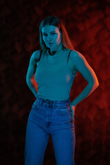 Young girl posing and moving in a black studio with colored light	