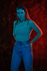 Young girl posing and moving in a black studio with colored light	