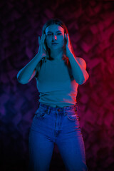 Young girl posing and moving in a black studio with colored light	