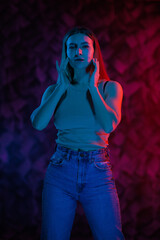 Young girl posing and moving in a black studio with colored light	