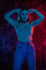 Young girl posing and moving in a black studio with colored light	