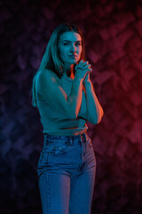 Young girl posing and moving in a black studio with colored light	
