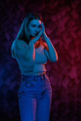 Young girl posing and moving in a black studio with colored light	
