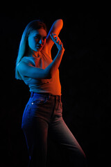 Young girl posing and moving in a black studio with colored light	