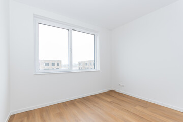 interior empty basic bedroom in modern new build residential smart house. Glass window is neighboring building over the road. Plain white walls and wood effect vinyl flooring make blank canvas