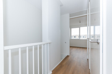 interior unfurnished empty basic corridor landing to room in modern new build residential smart house. Glass window view. Plain white walls and wood effect vinyl flooring make blank canvas