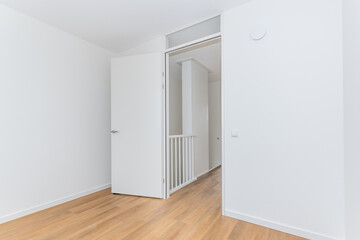 interior empty unfurnished basic room in modern new build residential smart house. Plain white walls and wood effect vinyl flooring make blank canvas open door to corridor landing