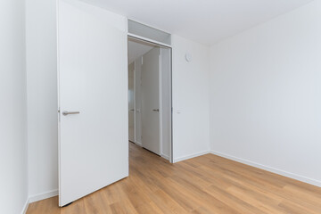 interior empty unfurnished basic room in modern new build residential smart house. Plain white walls and wood effect vinyl flooring make blank canvas open door to corridor landing