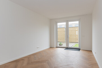 interior living room of modern new build residential smart house looking through glass patio door window at basic back garden plot with wooden shed. Brand new property freshly handed over to new owner