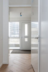 interior reception room of modern new build residential smart house looking through glass front door window at further development phase of project construction site building in scaffolding and crane