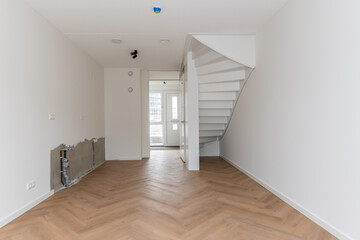 interior living room and bare kitchen fittings of modern new build residential smart house looking through glass front door window at further development phase of project construction site building