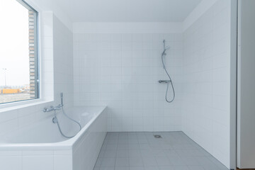 interior clean white tiled bath, shower and bathroom of modern new build residential smart house. unfurnished minimalist room