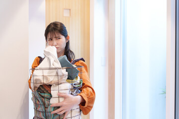 臭い洗濯物の臭いを嗅いで鼻をつまむ女性