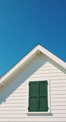 Minimalist white house facade with green shutter against clear blue sky