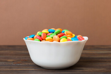 Multicolored candies in a bowl on a colored background. birthday and holiday concept. Top view with copy space