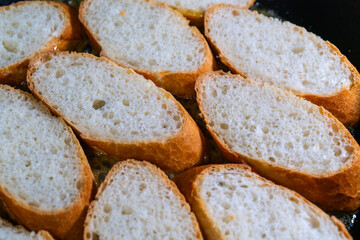 baking baguette slices with garlic sauce on the frying pan
