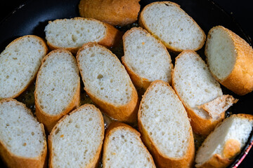 baking baguette slices with garlic sauce on the frying pan