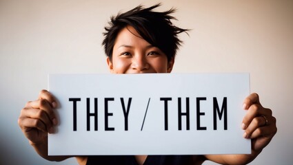White sign with text 'they/them' held by non-binary or genderfluid person