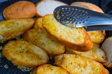 baking baguette slices with garlic sauce on the frying pan