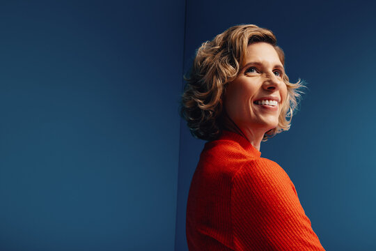 Confident middle-aged businesswoman in a vibrant monochromatic set with blue and orange colorblocking, looking determined