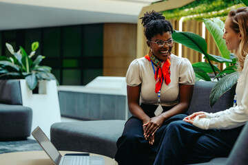 Two female coworkers having a casual meeting on a sofa