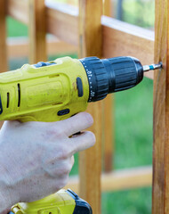 Person is using a drill to make a hole in a wooden board