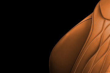 Brown leather interior of the luxury modern car. Perforated brown leather. Seats with stitching isolated on black background. Modern car interior details. Car inside